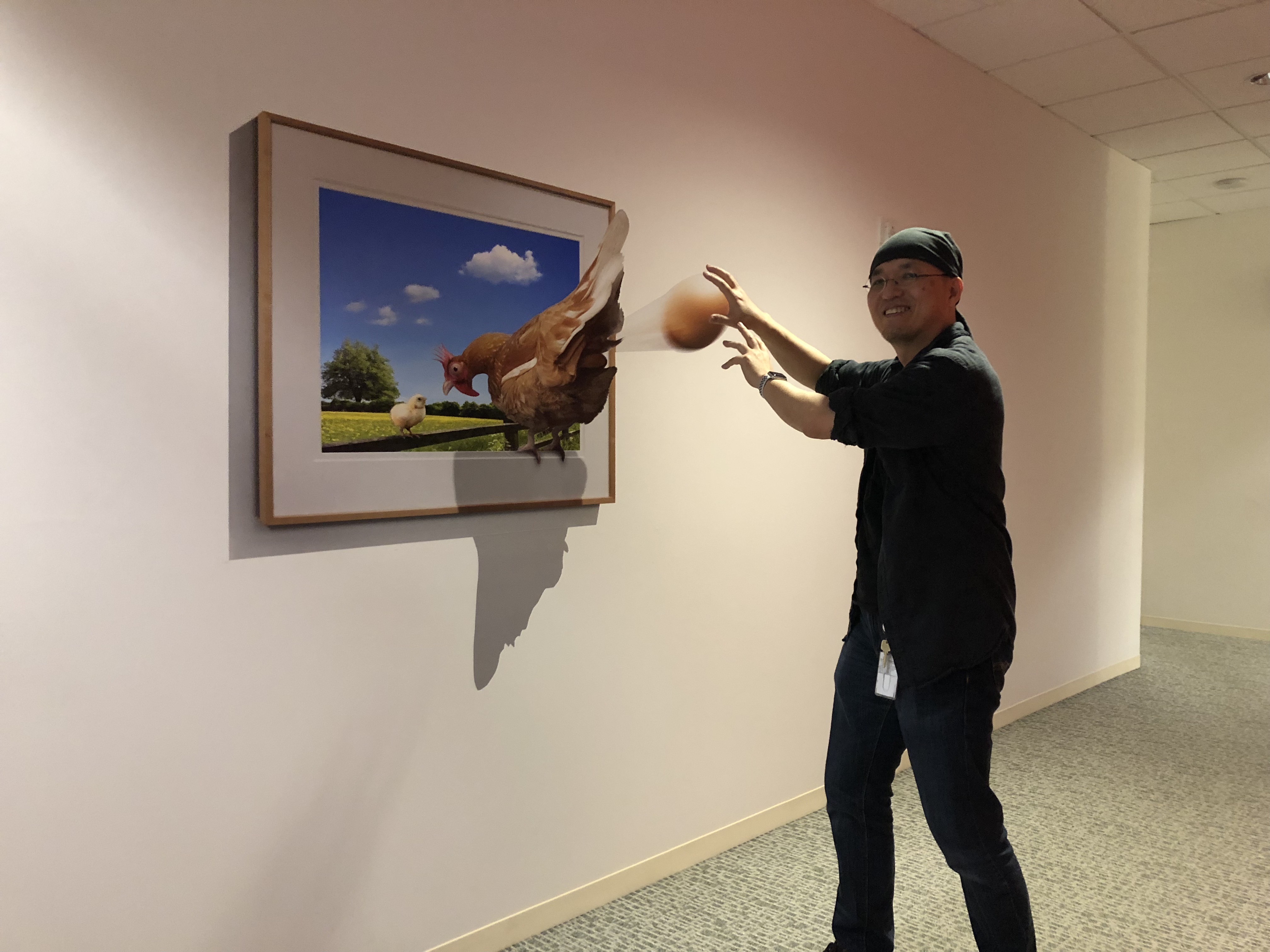 Catching an egg from a hen that appears to emerge from a framed picture